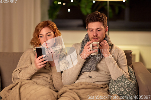 Image of sick young couple with smartphone at home