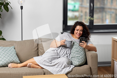 Image of woman with smartphone drinking coffee at home