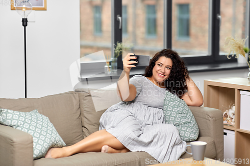 Image of happy woman taking selfie with smartphone at home