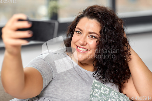 Image of happy woman taking selfie with smartphone at home