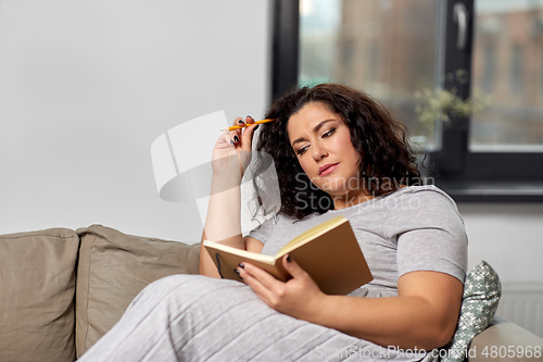 Image of young woman with diary on sofa at home