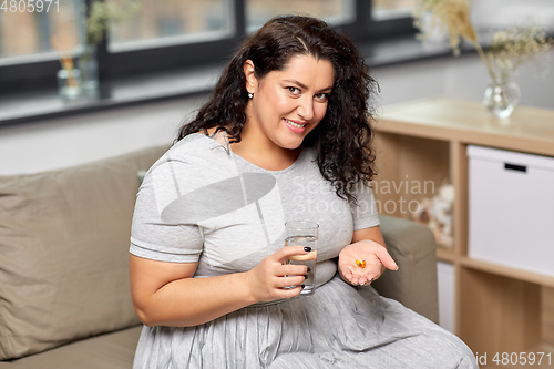 Image of woman with cod liver oil pills and water at home
