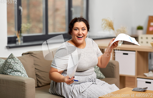 Image of happy woman with papers and calculator at home