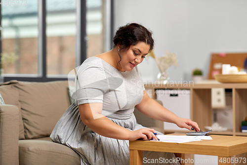 Image of woman with papers and calculator working at home