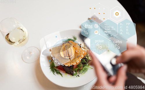 Image of hands with phone and food nutritional value chart