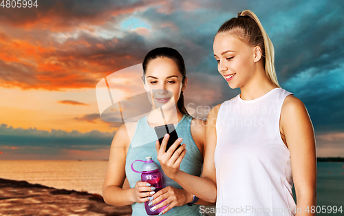 Image of women or female friends with smartphone and flask