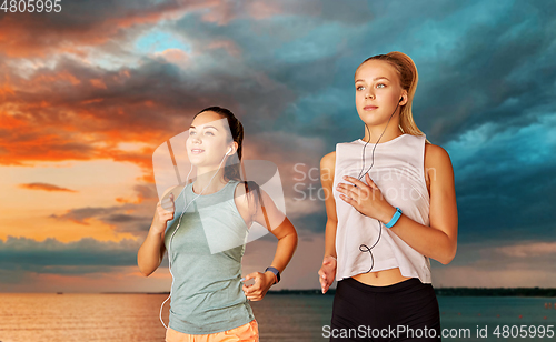 Image of women or female friends with earphones running