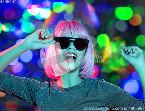 Image of happy woman in pink wig and sunglasses dancing