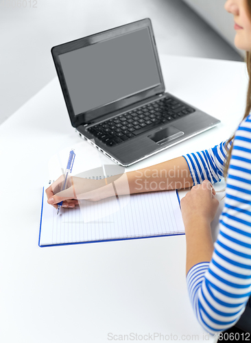 Image of student girl with exercise book, pen and laptop