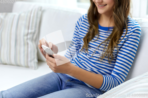 Image of smiling teenage girl using smartphone at home