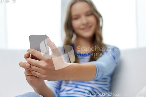 Image of smiling teenage girl using smartphone at home