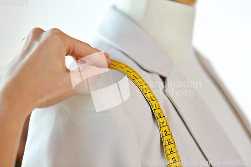 Image of fashion designer measures jacket with tape measure