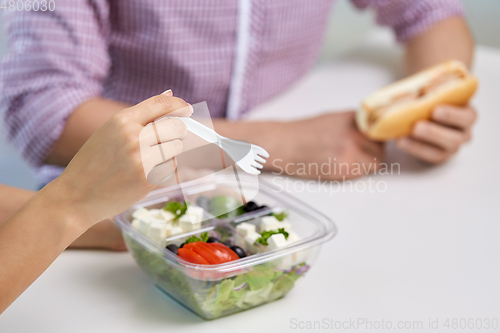 Image of hands of woman eating take out food from container