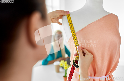 Image of fashion designer measuring dress with tape measure