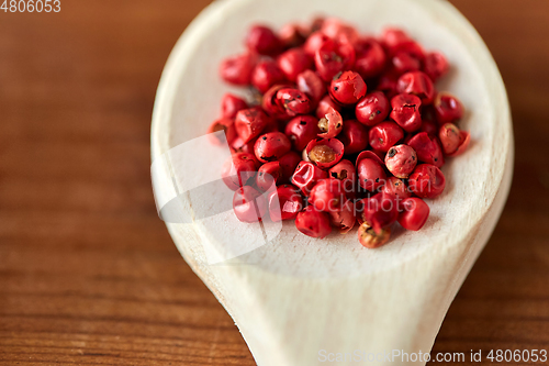 Image of close up of pink peppercorns on wooden spoon