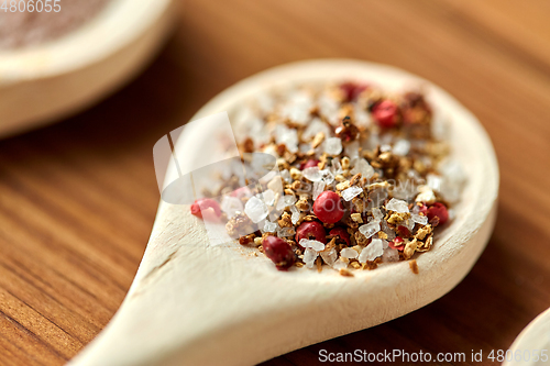 Image of spoon with salt and spices on wooden table