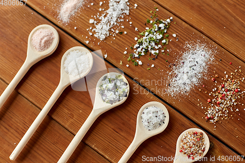 Image of spoons with salt and spices on wooden table