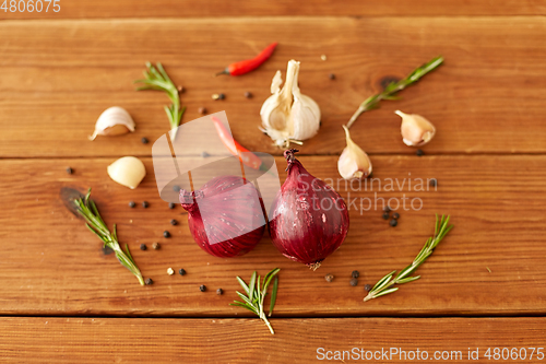 Image of onion, garlic, chili pepper and rosemary on table