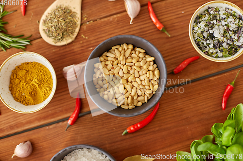 Image of pine nuts in bowl and spices on kitchen table
