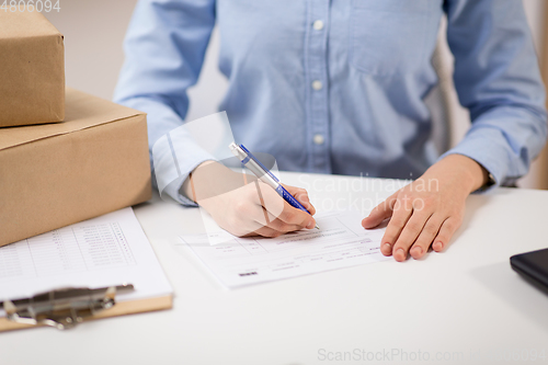 Image of close up of woman filling postal form at office