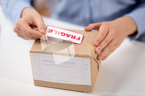 Image of woman sticking fragile mark to parcel box