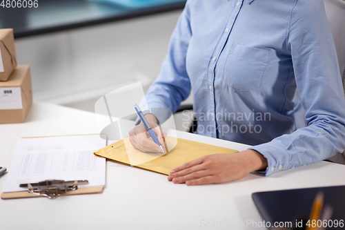 Image of woman writing on parcel envelope at post office