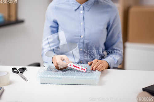 Image of woman sticking fragile mark to wrap at post office