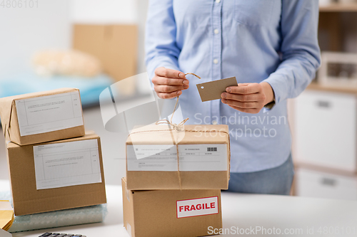 Image of woman packing parcel and tying tag at post office