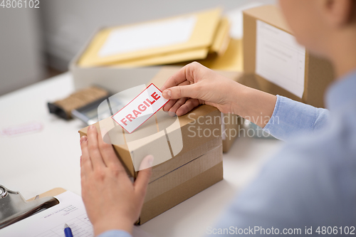 Image of woman sticking fragile mark to parcel box