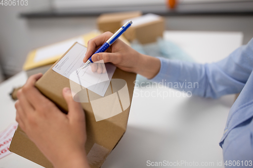 Image of close up of woman filling postal form at office