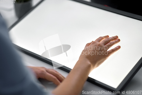 Image of hand on led light tablet at night office