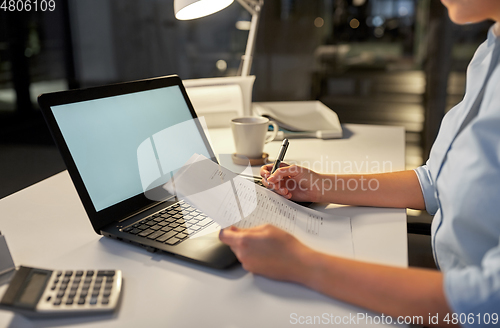 Image of businesswoman with papers working at night office