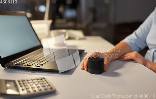 Image of hand using smart speaker at night office