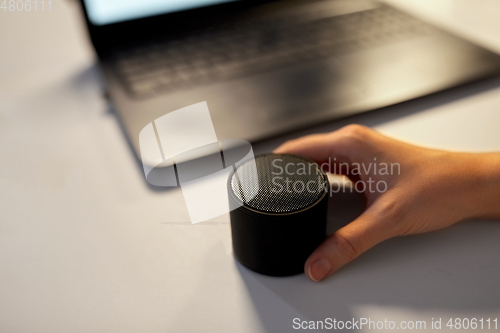 Image of hand using smart speaker at night office