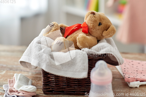 Image of teddy bear toy in basket with baby things on table