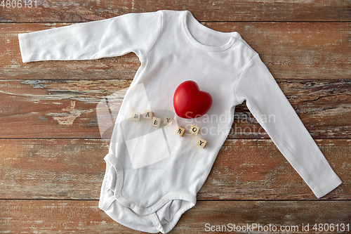 Image of baby boy's bodysuit with red heart on wooden table