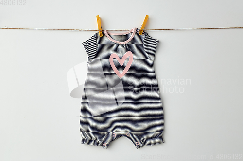 Image of bodysuit for baby girl hanging on rope with pins