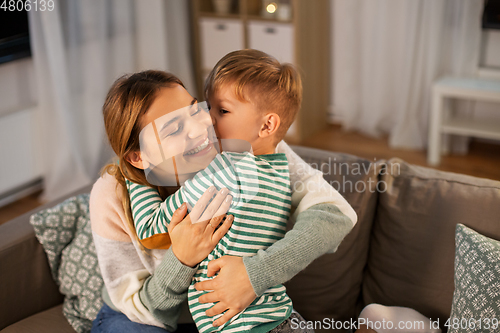 Image of happy mother and son hugging and kissing at home