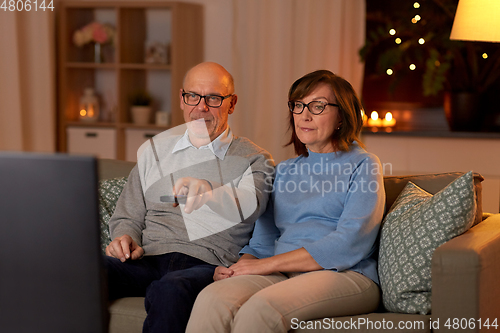 Image of senior couple watching tv at home in evening