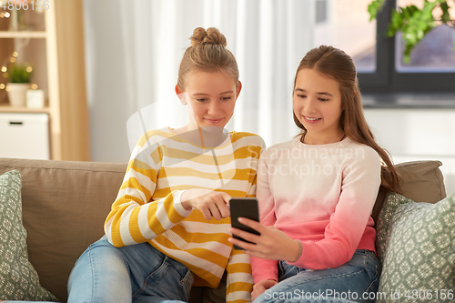 Image of happy teenage girls with smartphone at home