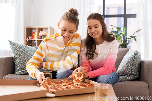 Image of happy teenage girls eating takeaway pizza at home