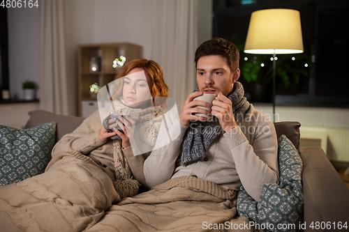 Image of sick young couple drinking hot tea at home