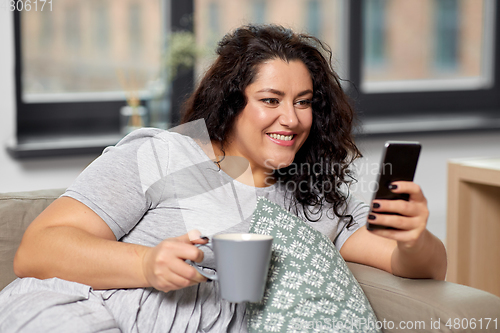 Image of woman with smartphone drinking coffee at home