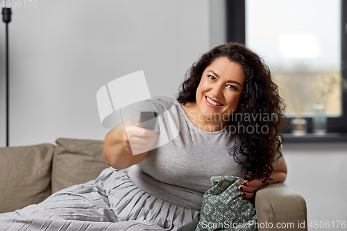 Image of woman with remote control and watching tv at home