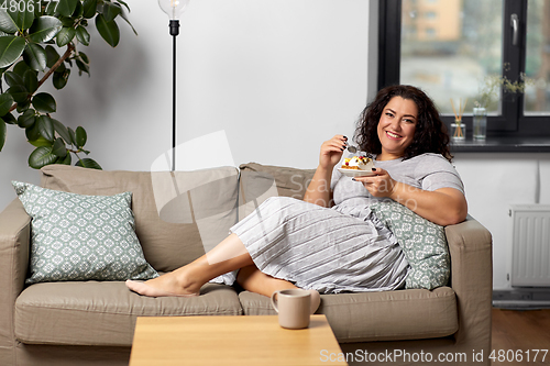 Image of smiling young woman eating cake at home
