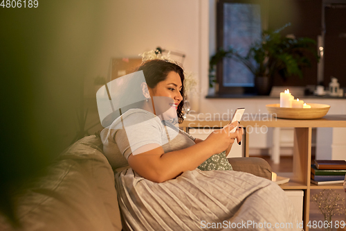 Image of woman with smartphone at home in evening