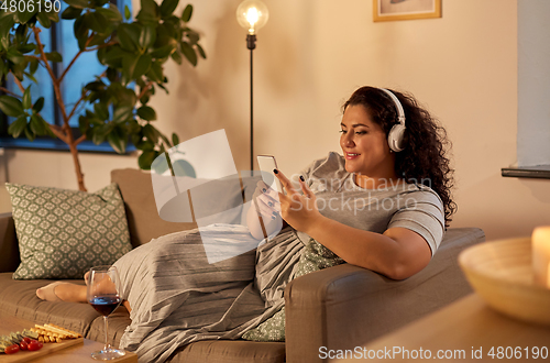 Image of woman in headphones listens to music on smartphone