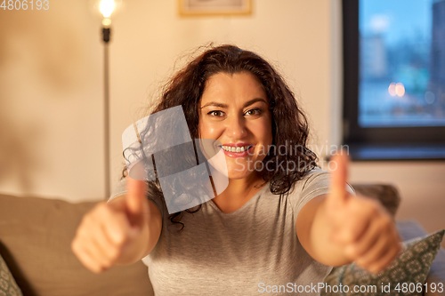 Image of happy smiling woman showing thumbs up at home