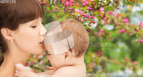 Image of close up of happy mother kissing baby over garden