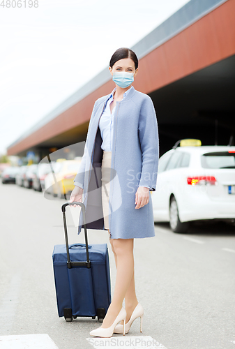 Image of woman with travel bag in protective mask in city